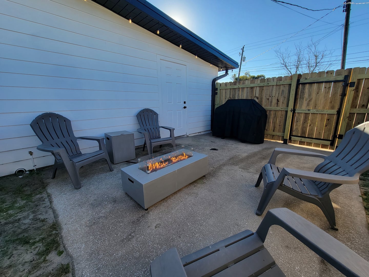 Private fenced patio with Adirondack seating and a gas fire table for relaxed evenings outdoors.